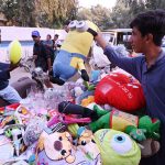 A vendor sells baby dolls and other toys from his handcart along the roadside in the city