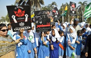 Students carry posters during a Kashmir Black Day rally organised by Commissioner Karachi Syed Hasan Naqvi from Peoples Chowrangi to Mazar-e-Quaid to protest against alleged Indian atrocities and express solidarity with the people of Kashmir.