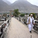An elderly man walks across the historic suspension bridge in Konodass, Gilgit