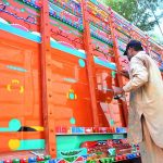 A painter busy in color paint on the body of truck at his workplace