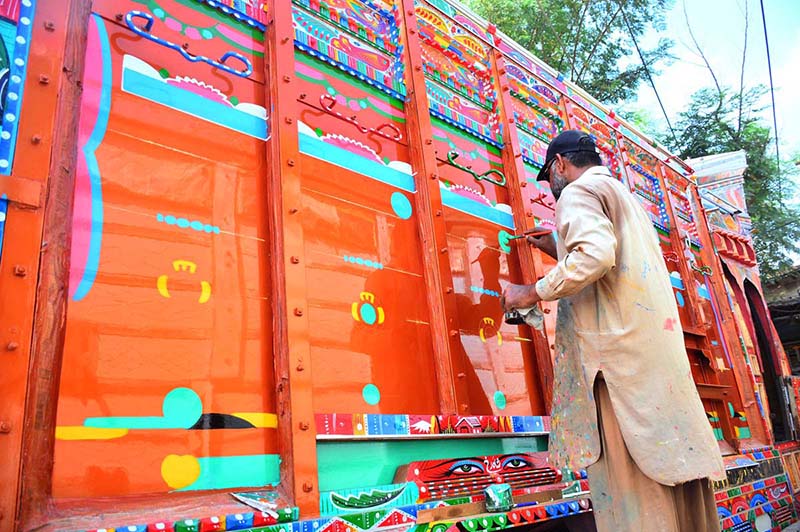 A painter busy in color paint on the body of truck at his workplace