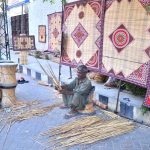 A worker preparing and displaying traditional curtains (chicks) at his roadside setup near Court road