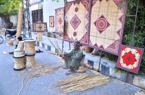 A worker preparing and displaying traditional curtains (chicks) at his roadside setup near Court road