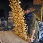 A labourer cleaning peanuts in a traditional way at Firdous Market