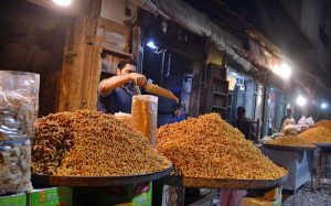 A shopkeeper decorates different types of 'besan ki bondiyas' to attract customers in Ghala Mandi.