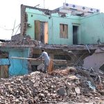 A house is being demolished during an anti-encroachment operation carried out on the instructions of Deputy Commissioner Afaq Wazir, while family members remove belongings and debris from the demolished structure along Ring Road