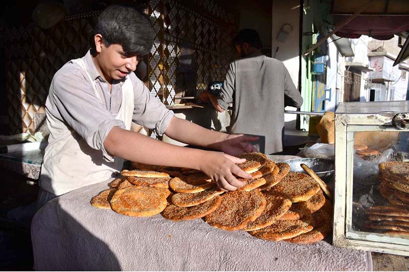 A worker displays freshly baked roghni naan for sell at a tandoor